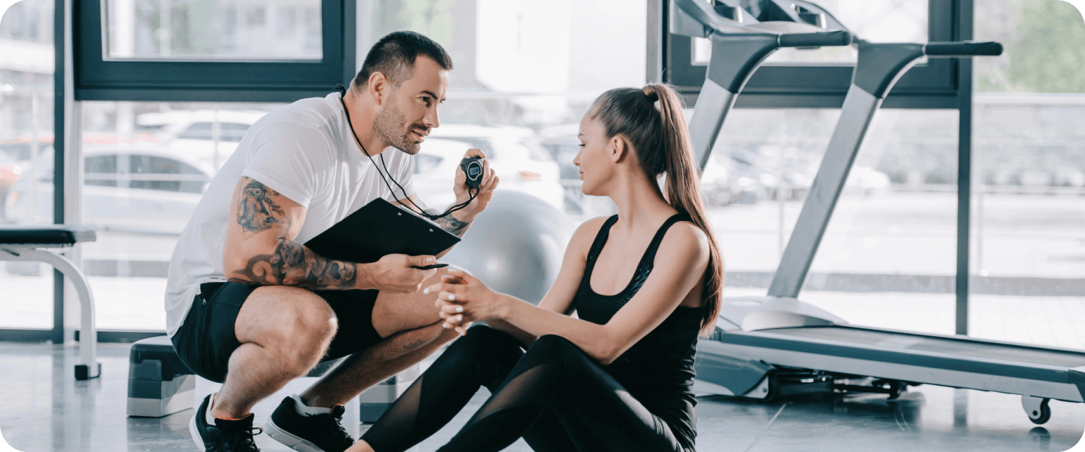 Male fitness coach showing timer and consulting client